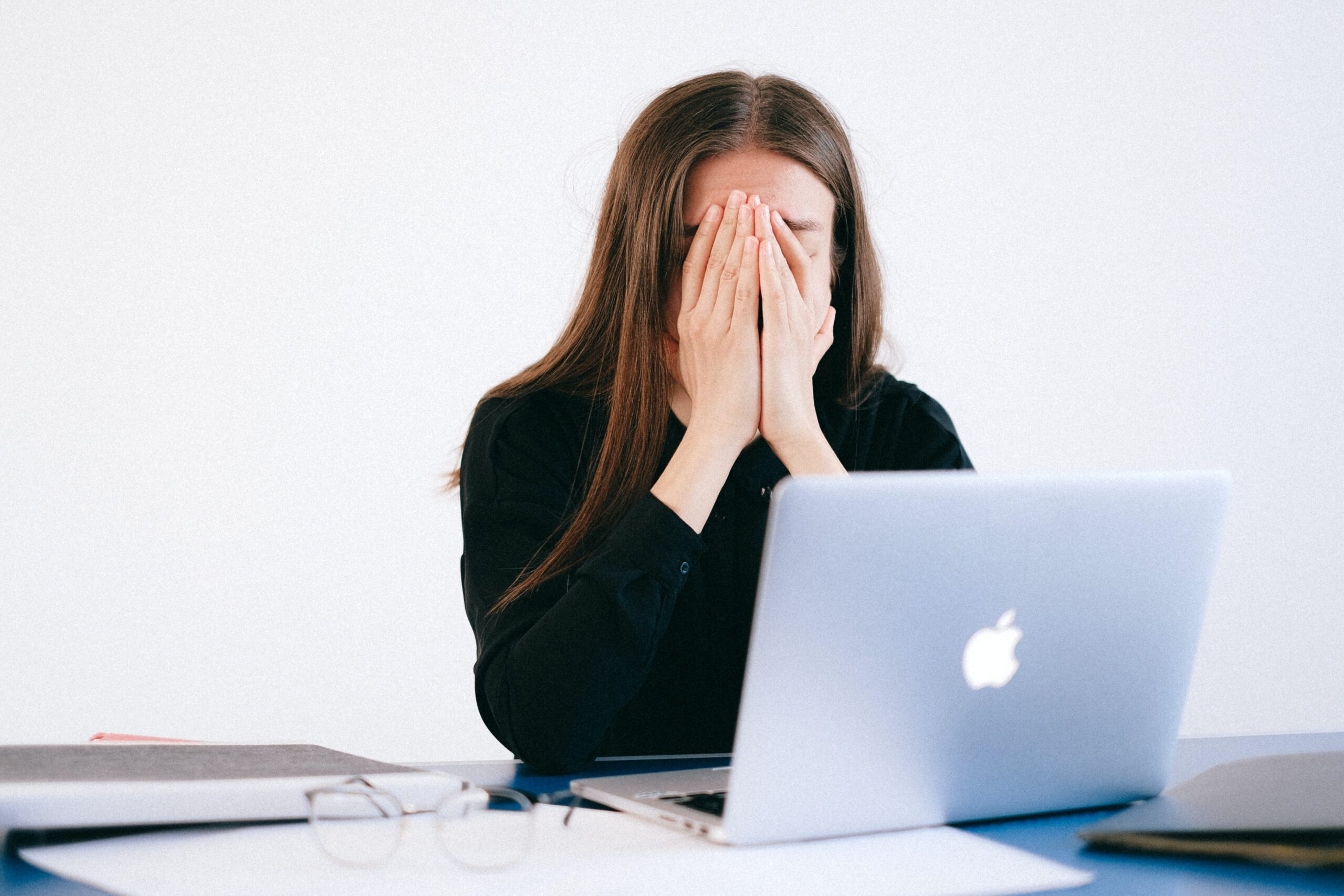 Stressed woman holding her head while sitting in front of her laptop