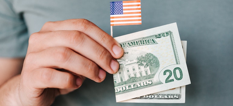 A man holding money and a tiny flag.