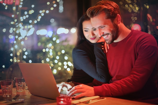 Happy couple sitting at a desk and browsing homes online