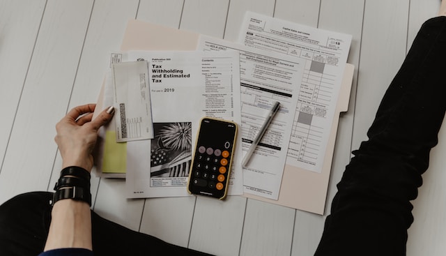 A person using a phone to calculate budget and taxes while sitting on the floor