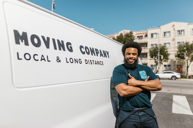 Professional standing next to a white moving van for relocating to luxury homes