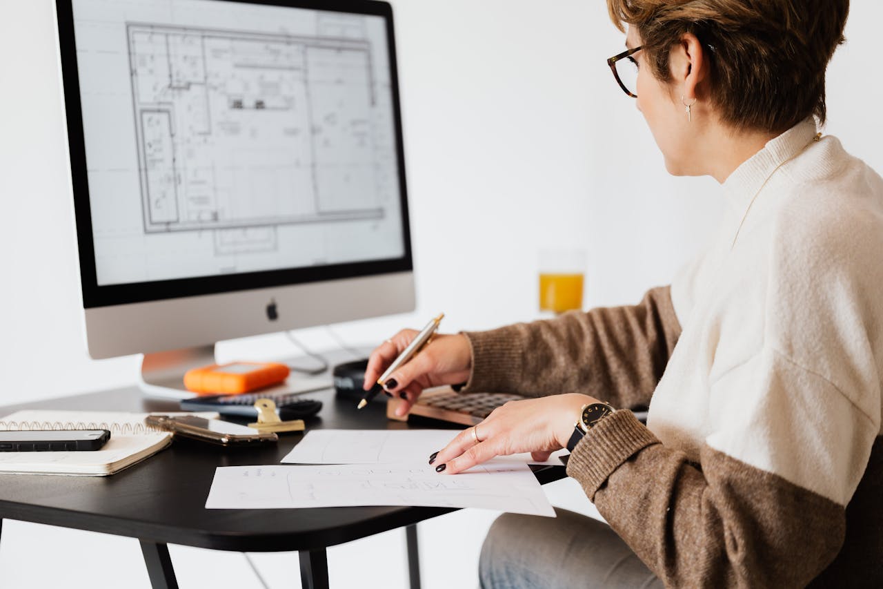 A woman looking at a floor plan on a computer, performing luxury property appraisal