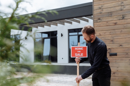 a real estate agent with a home for sale sign